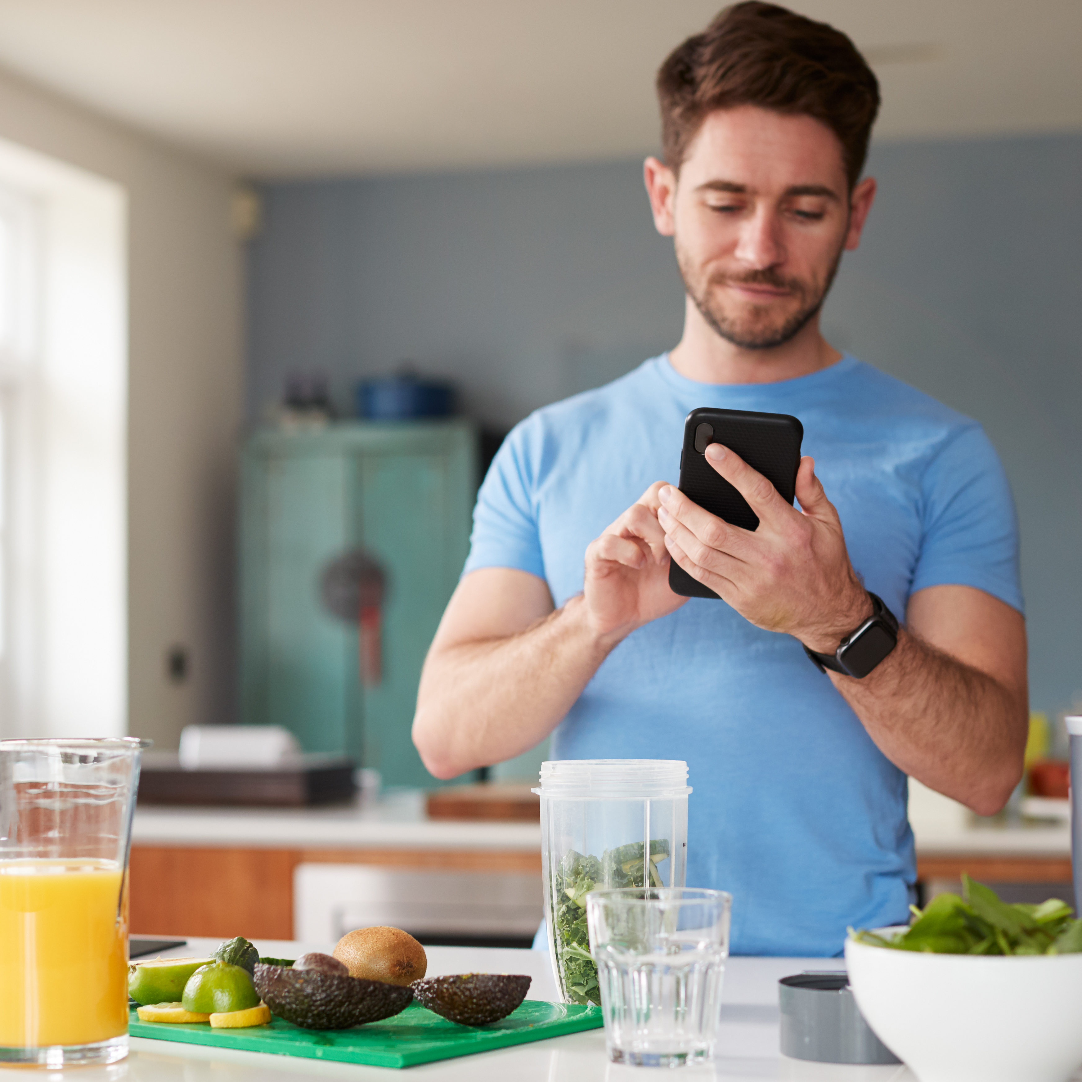 Man Using Fitness Tracker To Count Calories For Post Workout Juice Drink He Is Making